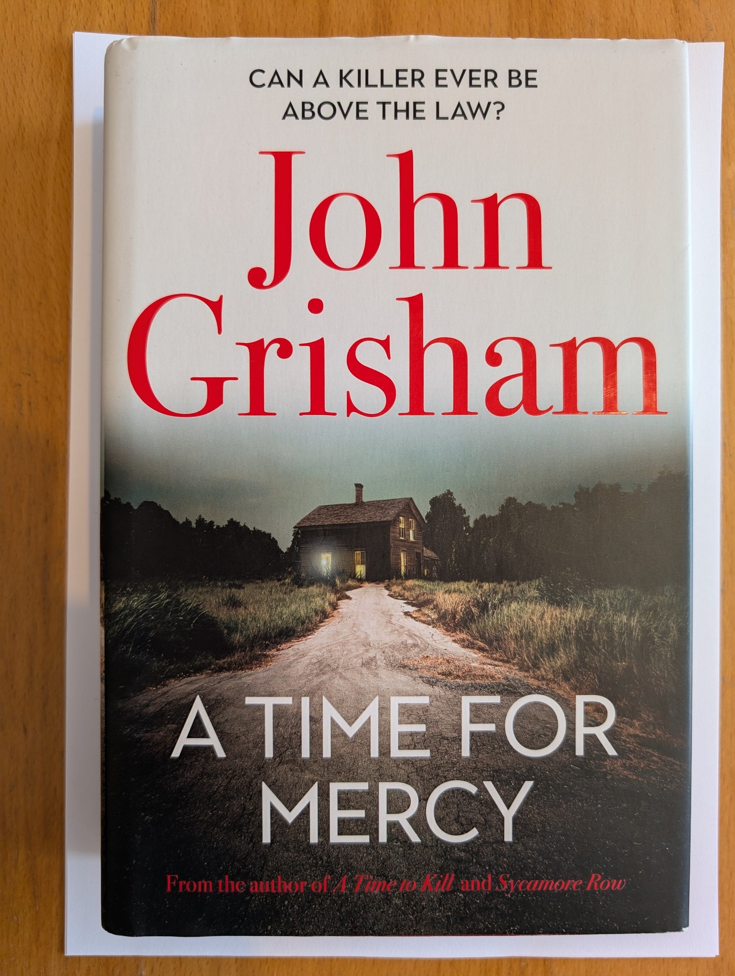 Book cover of 'A Time for Mercy' by John Grisham on a wooden surface