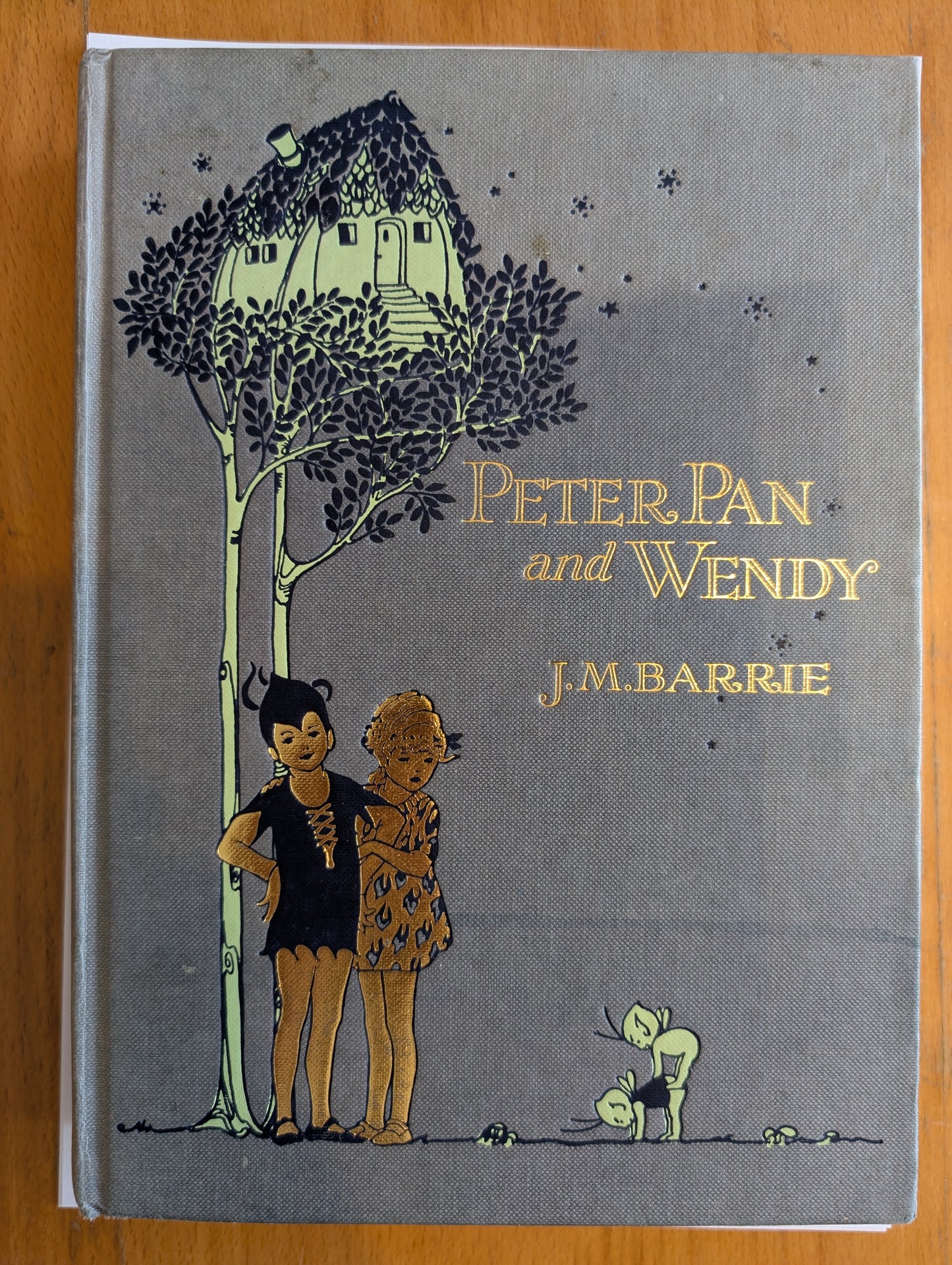 Book cover of 'Peter Pan and Wendy' by J.M. Barrie on a wooden surface