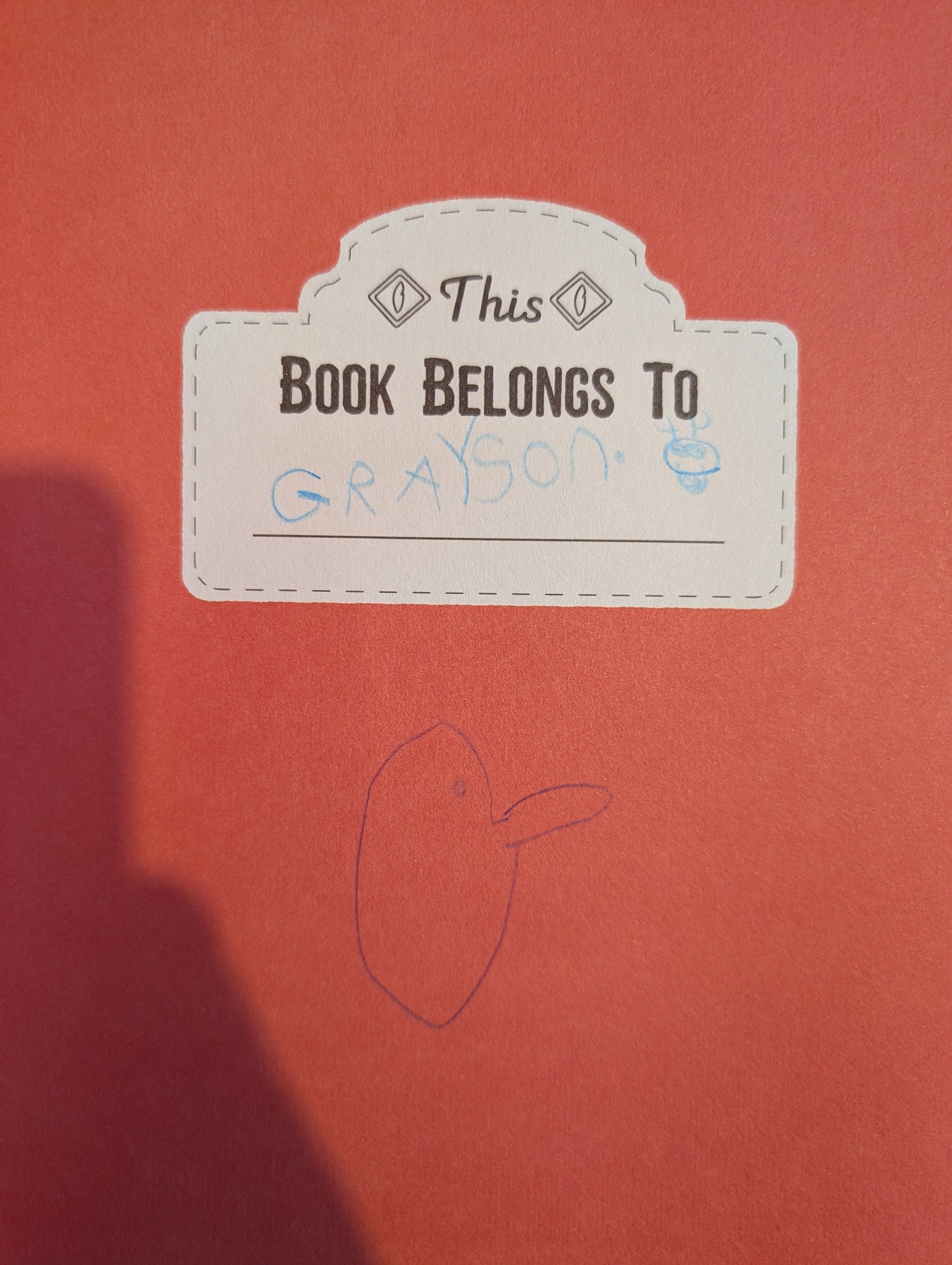 Label on a red book with text and a drawing of a face.