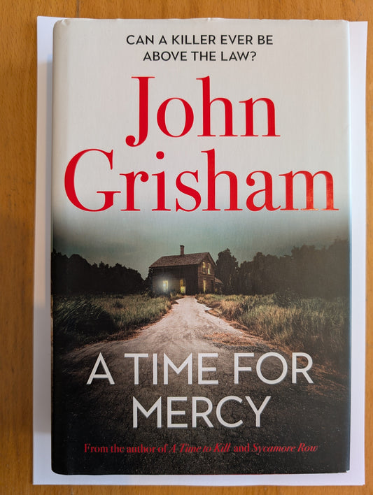 Book cover of 'A Time for Mercy' by John Grisham on a wooden surface