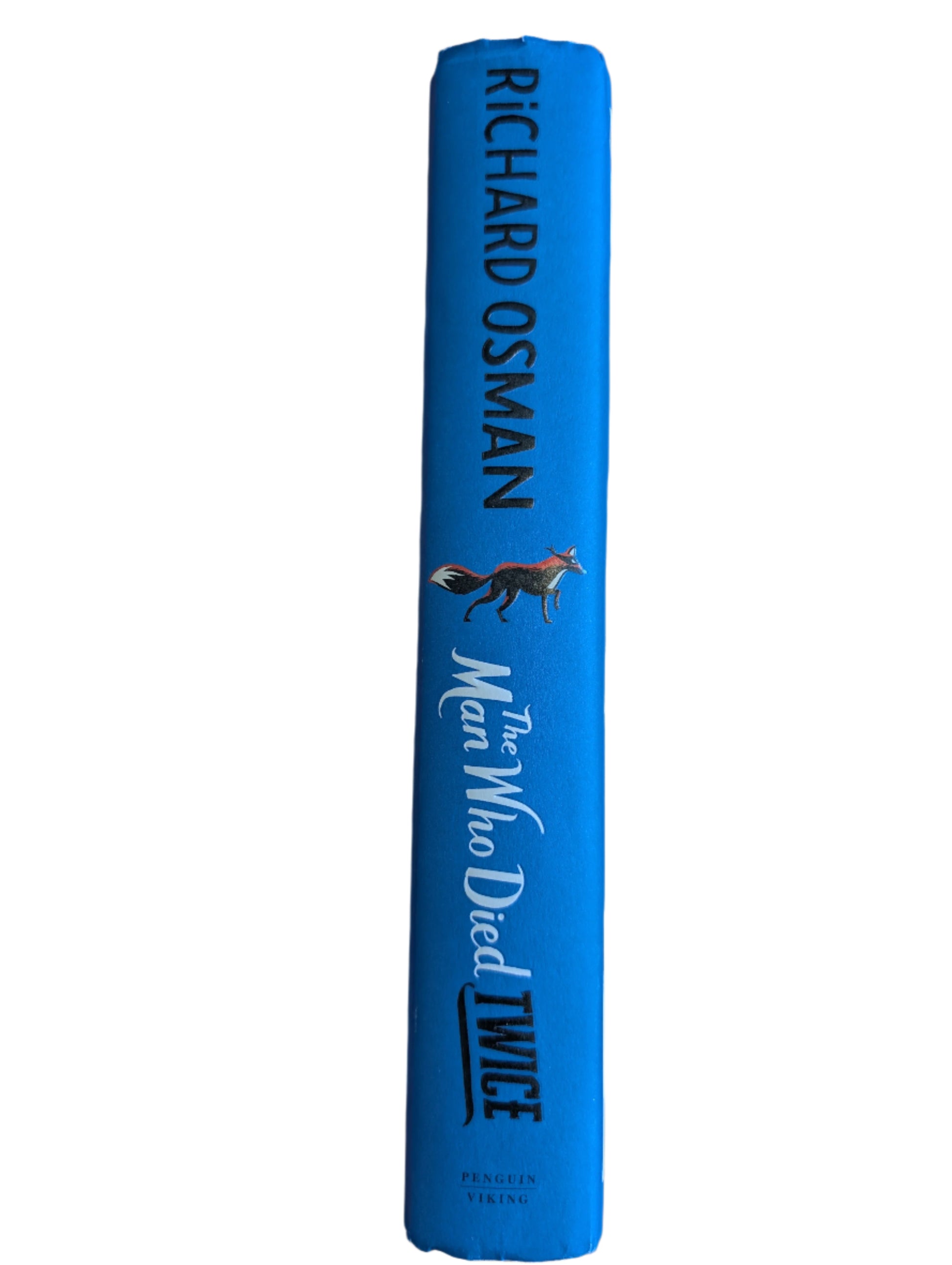 Blue book titled 'The Man Who Died Twice' by Richard Osman on a wooden surface.