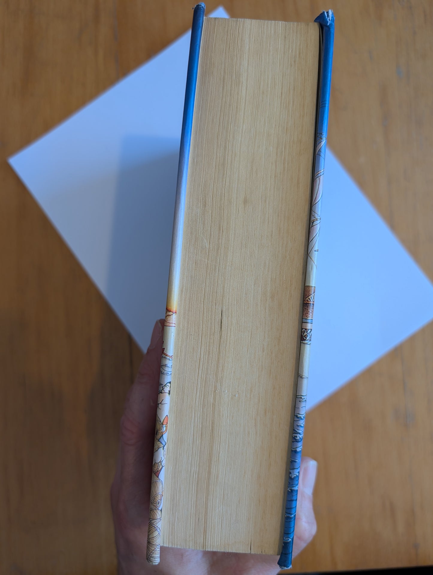 Book held open with a wooden surface and white paper in the background