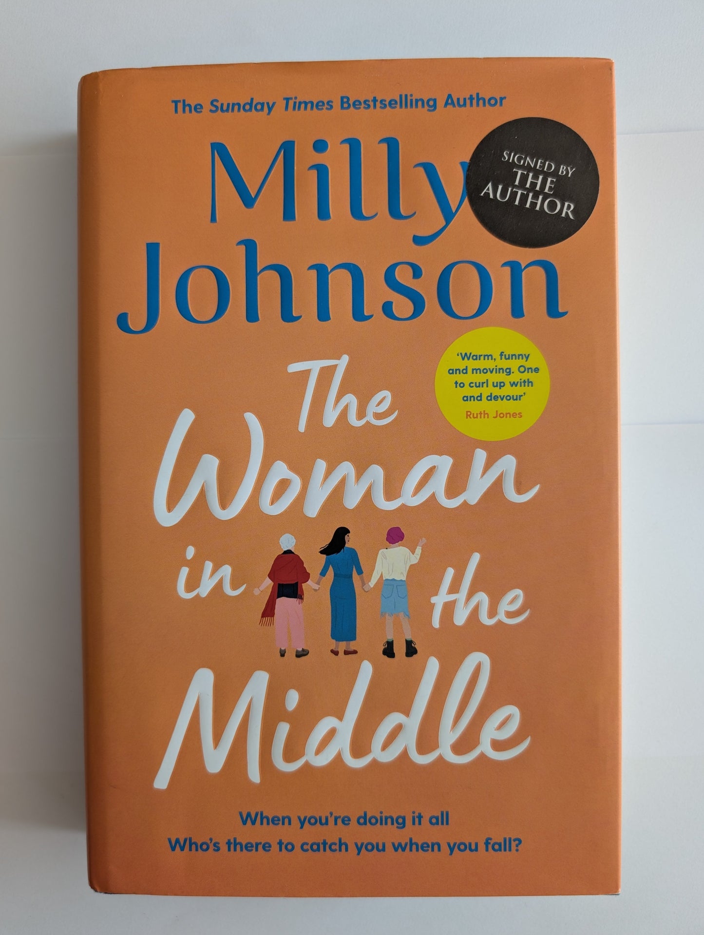 Book titled 'The Woman in the Middle' by Milly Johnson on an orange background